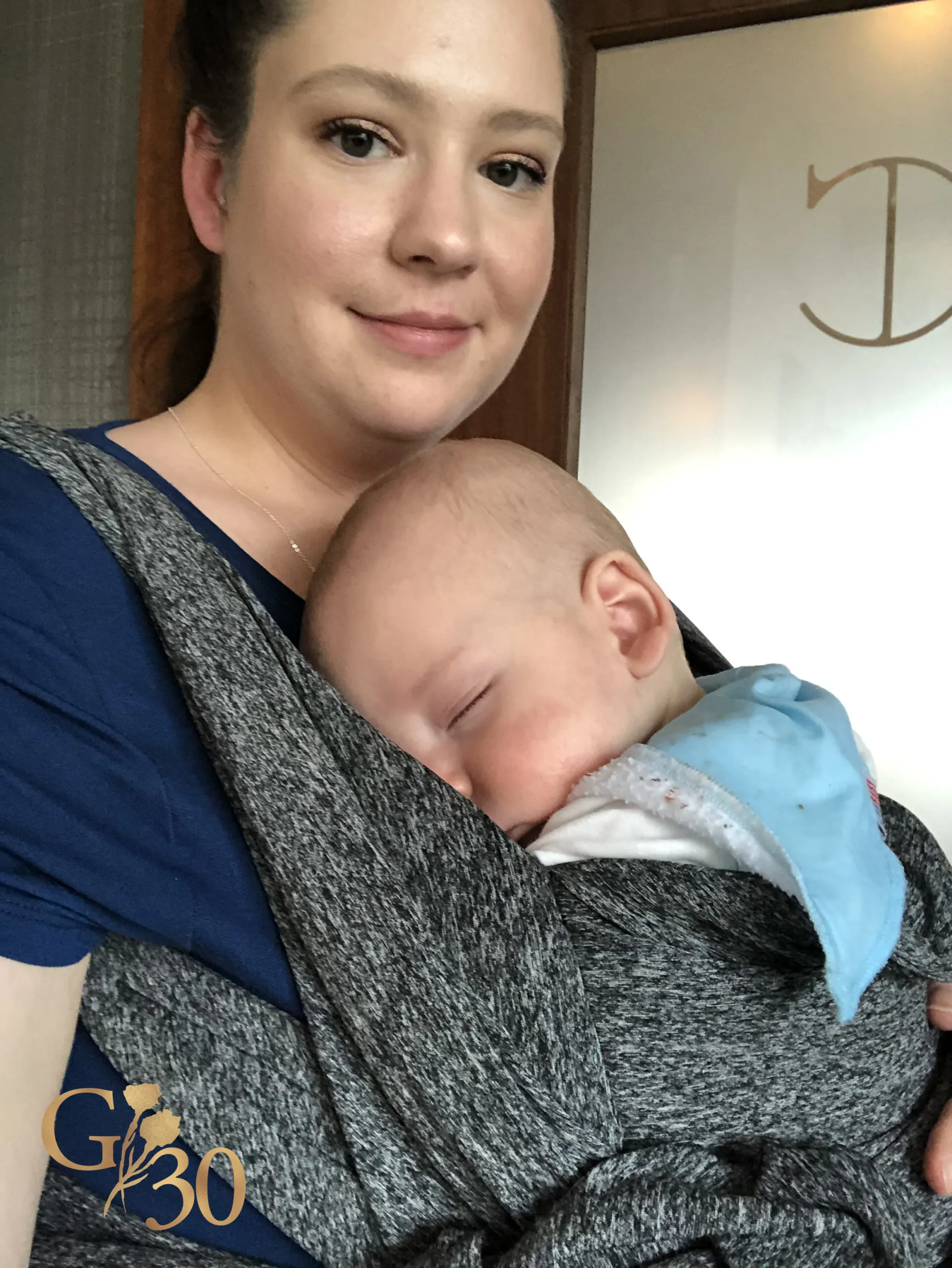 woman wearing a sleeping baby in a baby carrier