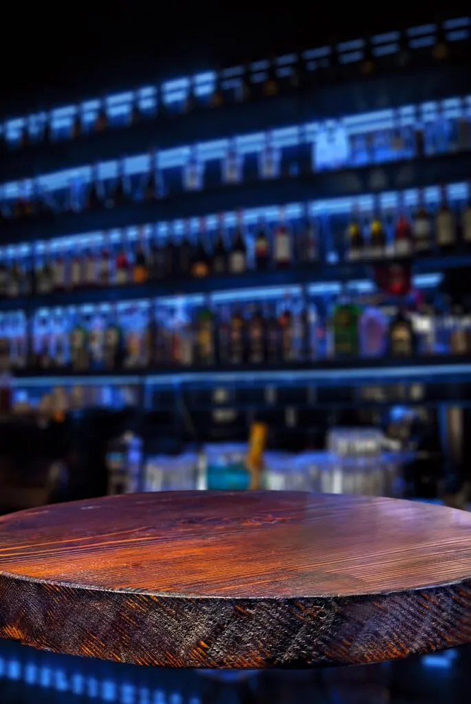 Wooden board on a background of bottles with alcohol