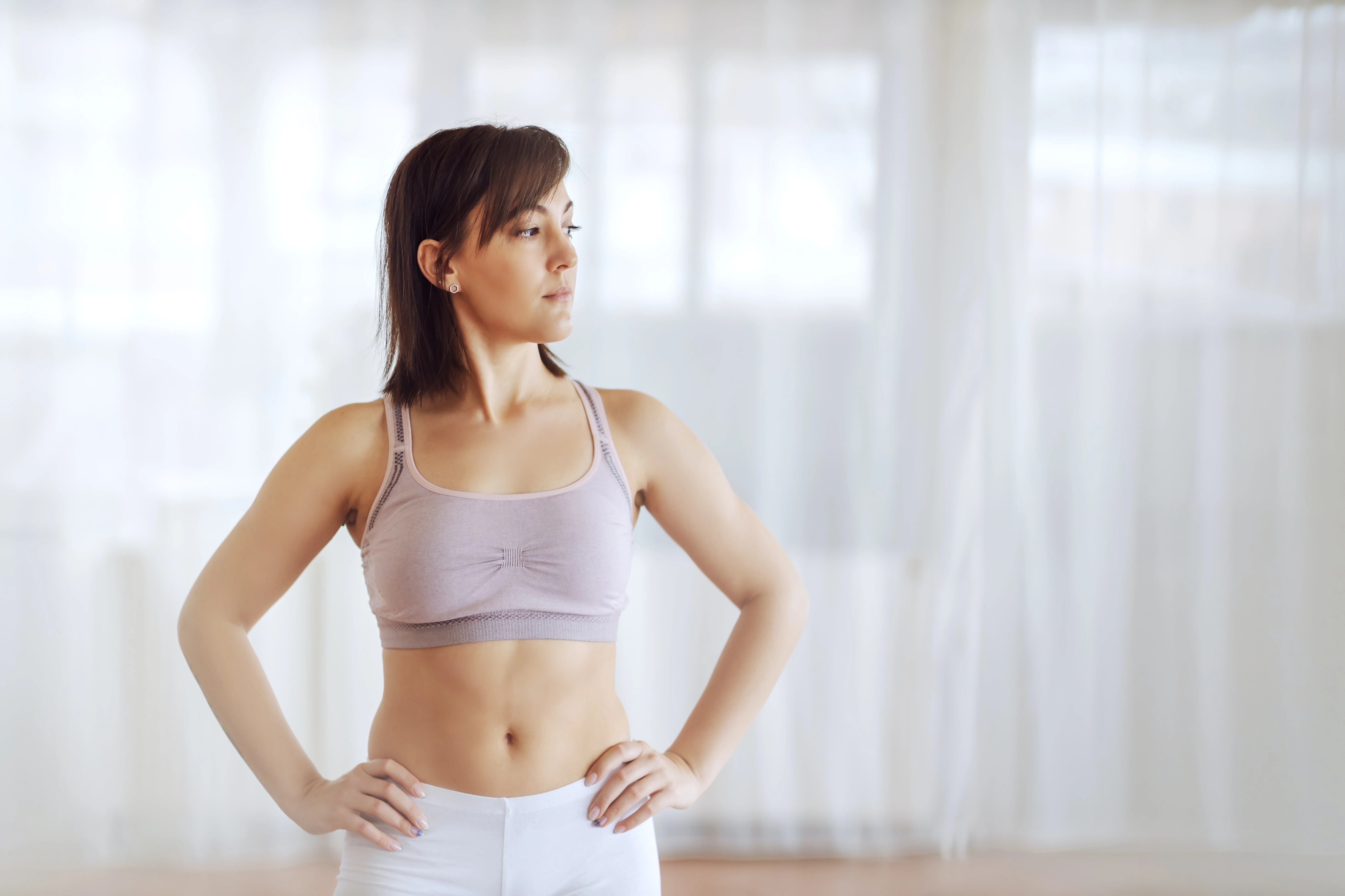 woman standing wearing a grey sports bra 