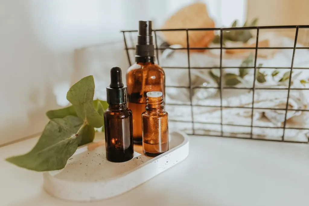 amber skincare bottles on a white tray with towels in the background