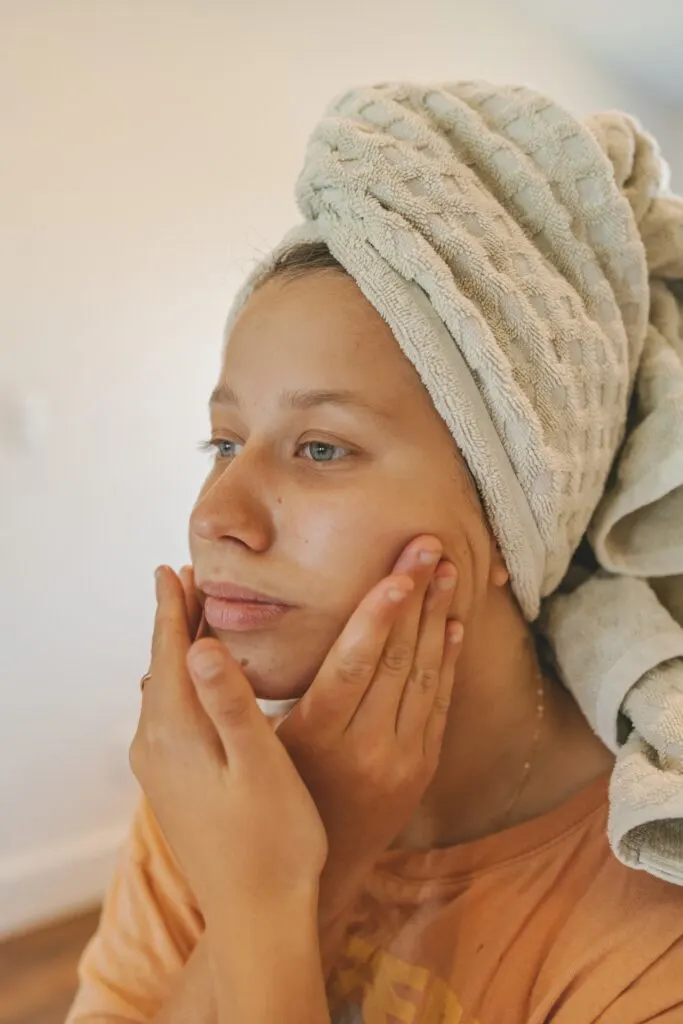 woman doing lymphatic massage to herself with a towel on her head