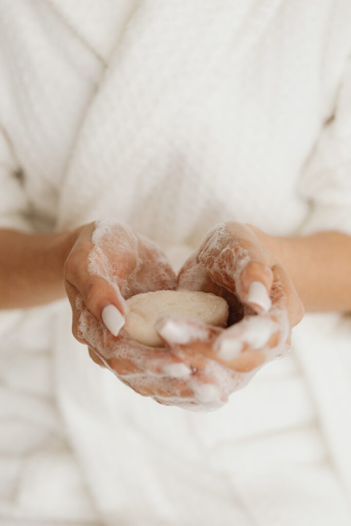 woman in a robe holding a cleansing bar