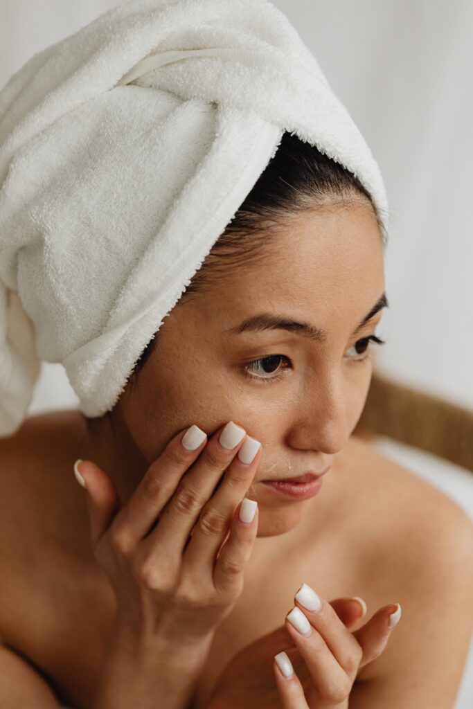 woman washing her face with a white towel on her head
