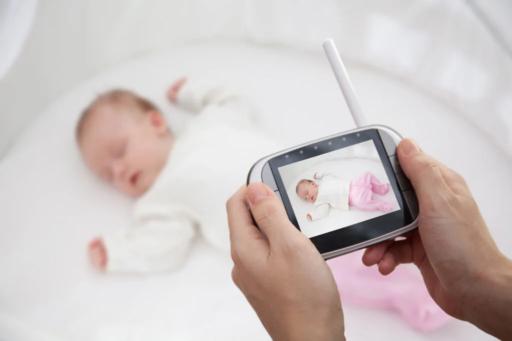 mom looking at baby monitor by sleeping baby