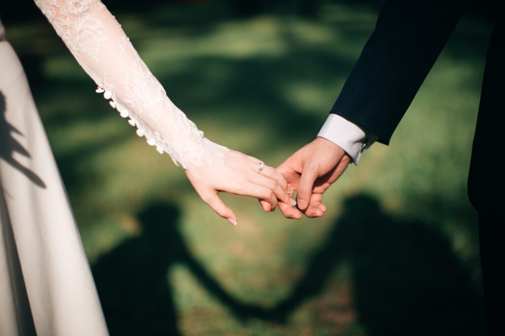 Didn't Get Married Until Their 30s. A close up of the hands of a bride and groom holding hands on a sunny day.
